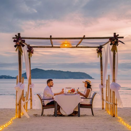 couple having a romantic dinner on the beach of Phuket Thailand during sunset